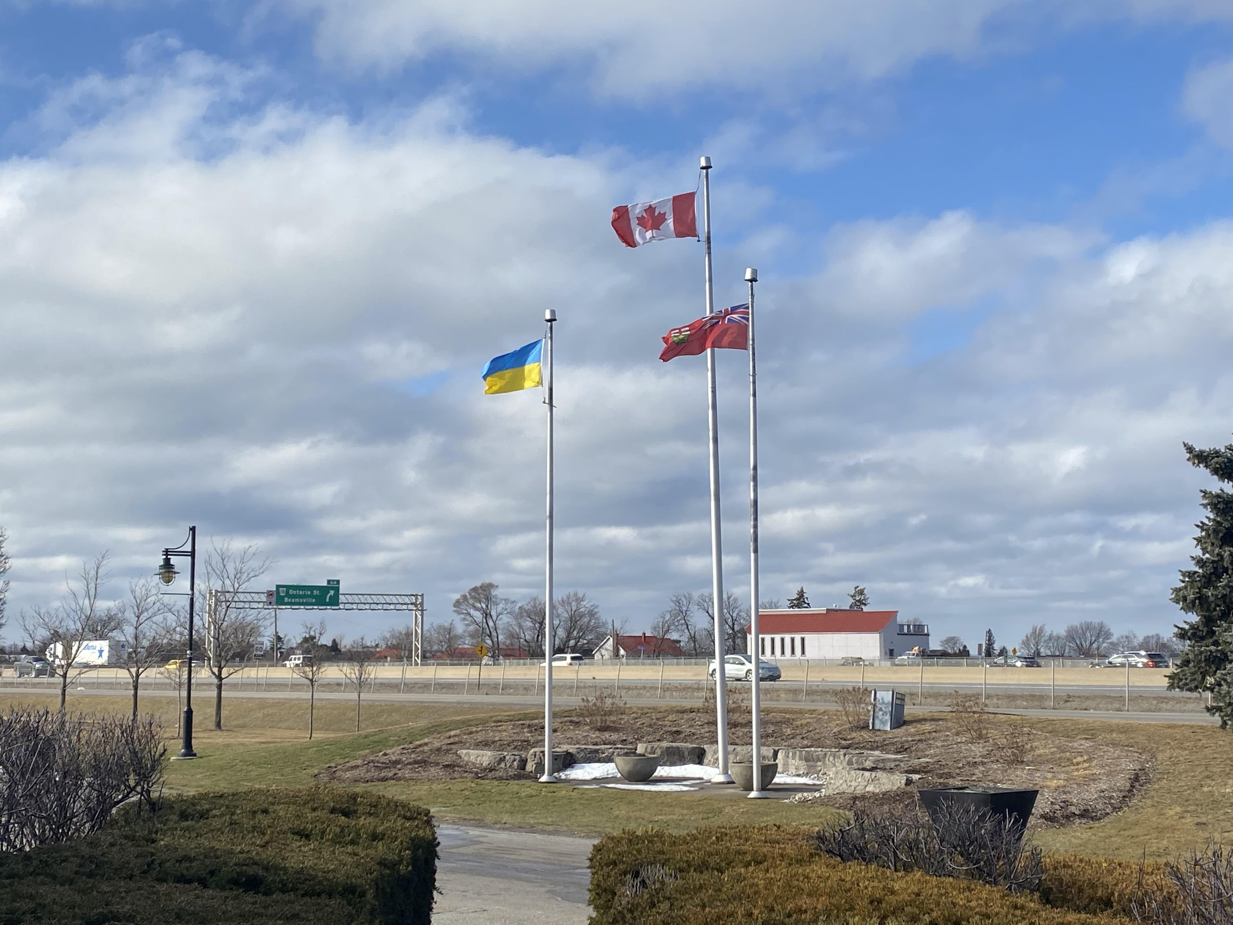 Three flagmasts. One is flying the Ukrainian flag, one is flying the Canadian flag, and the last one is flying Ontario's flag.
