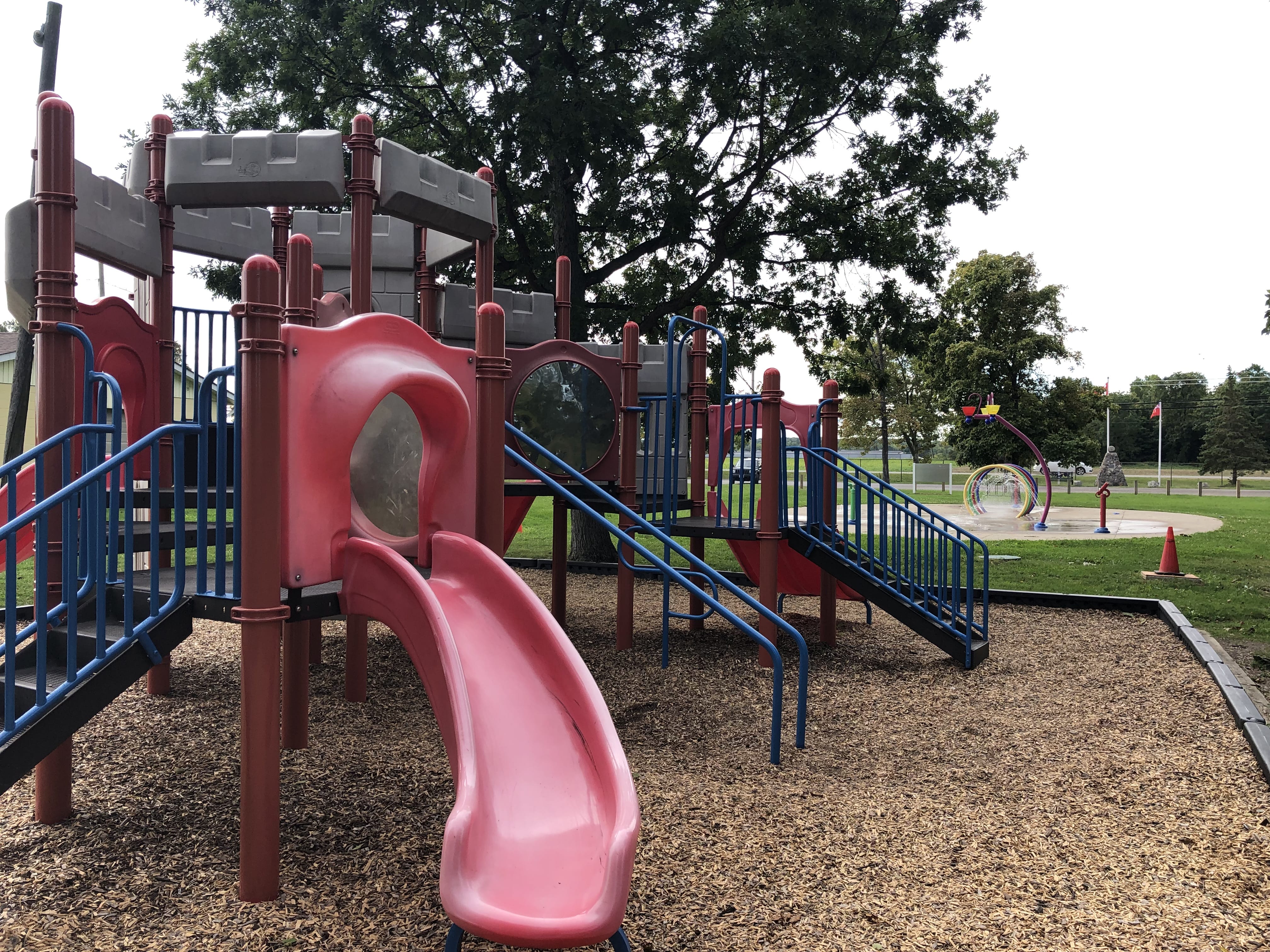 Red slide and jungle gym in playground.