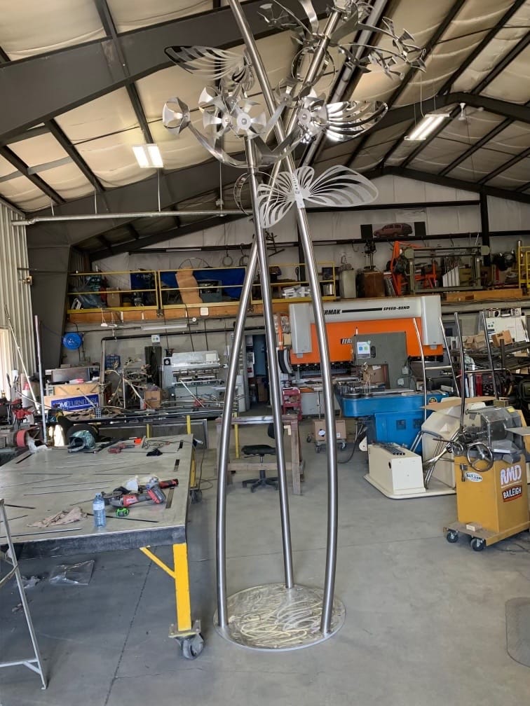 Metal sculpture of butterflies. The sculpture is inside a workshop.
