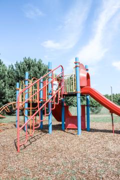 A blue and red playground with red metal climbing stairs and a red slide.