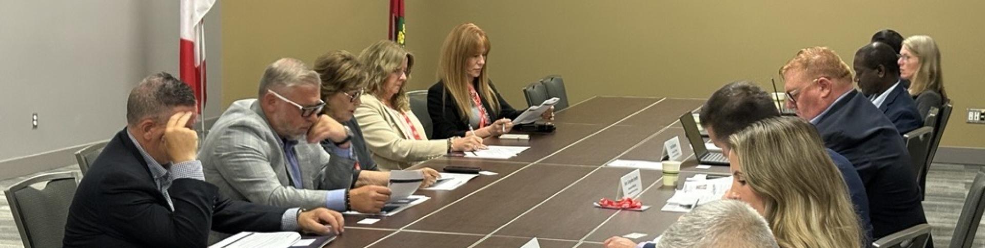 People sitting on either side of a long table in a room.
