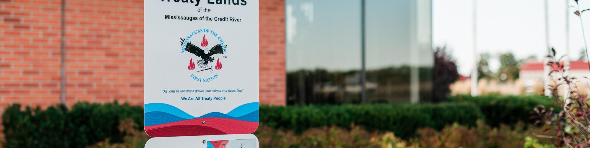 Outdoor sign in front of a building and garden.