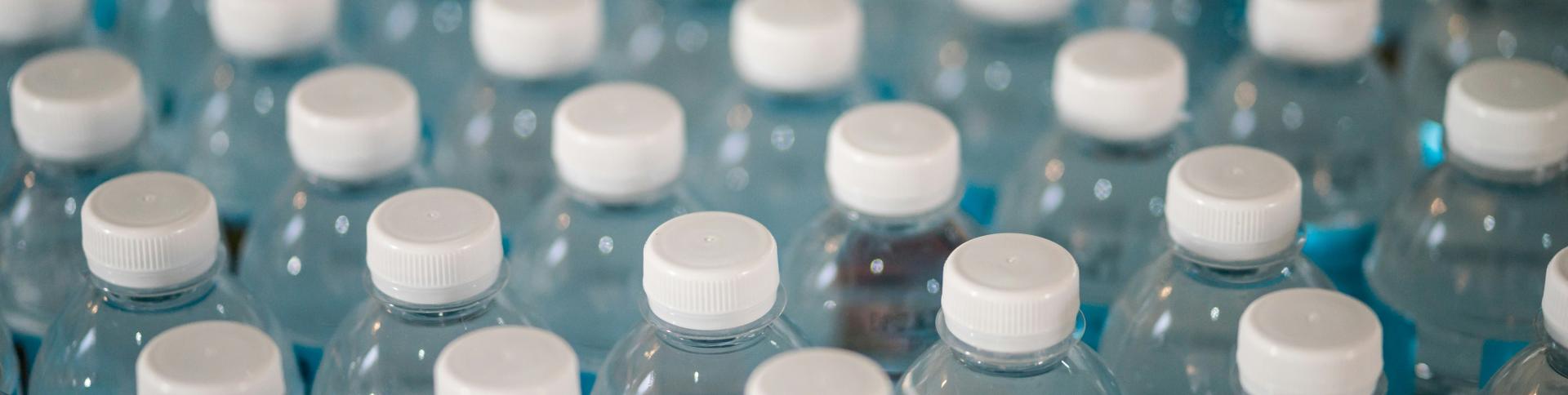 Lots of water bottles grouped together with the camera showing the top quarter of them.