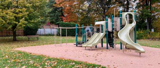 Playground equipment with slides and a bench and trees
