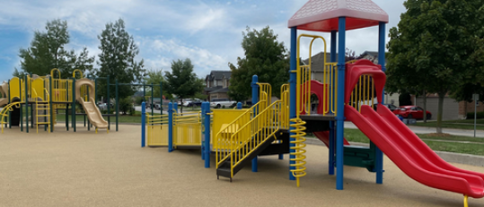 Multiple playground equipment sets with trees in the background