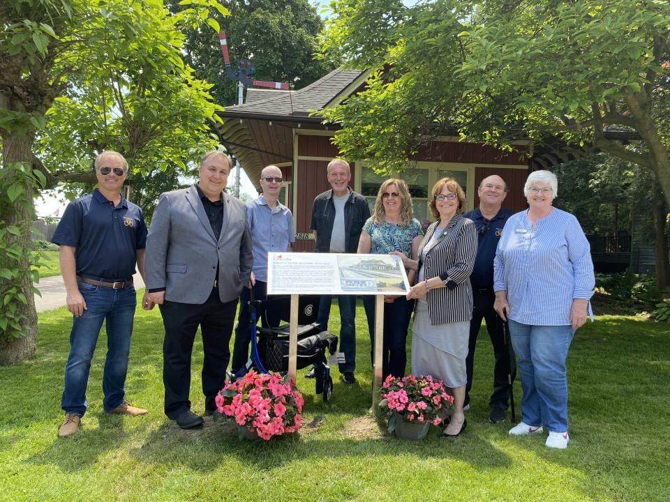 Group of council members standing behind a plaque.