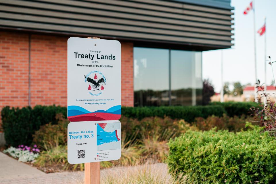 Outdoor sign in front of a building and garden.