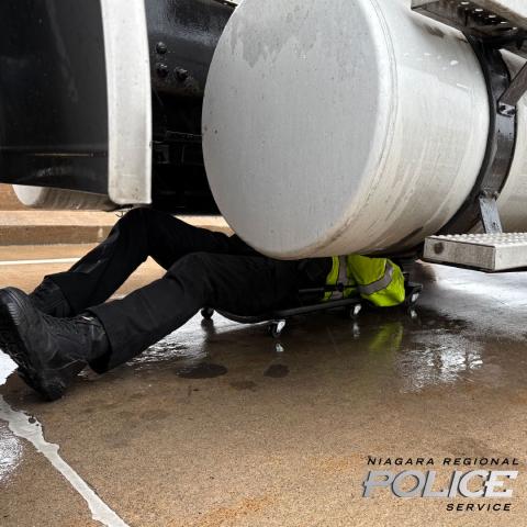 Police officer under truck completing an inspection