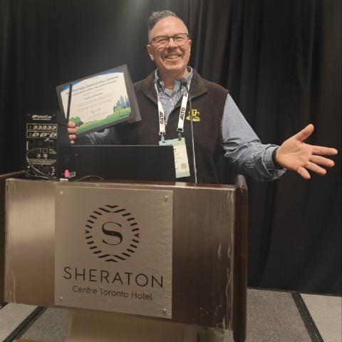 Man behind podium holding up award